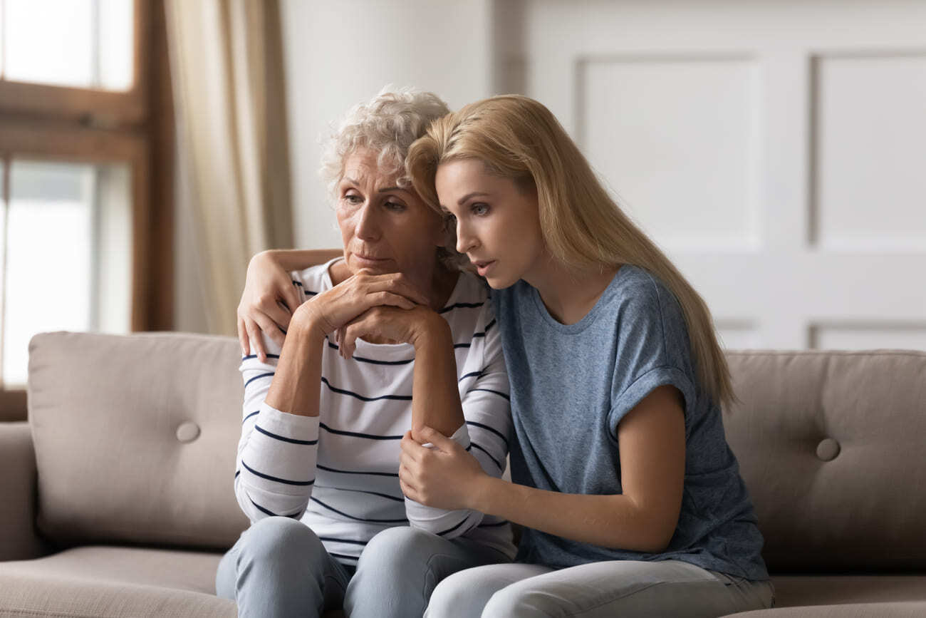 Two women are sitting embraced on the couch.