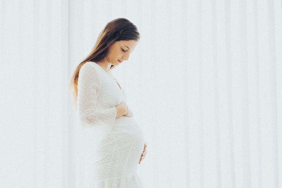 אישה צעירה בהריון, אוחזת ומביטה בבטן שלה