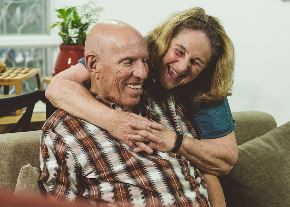 Elderly woman hugging her partner from behind, both laughing