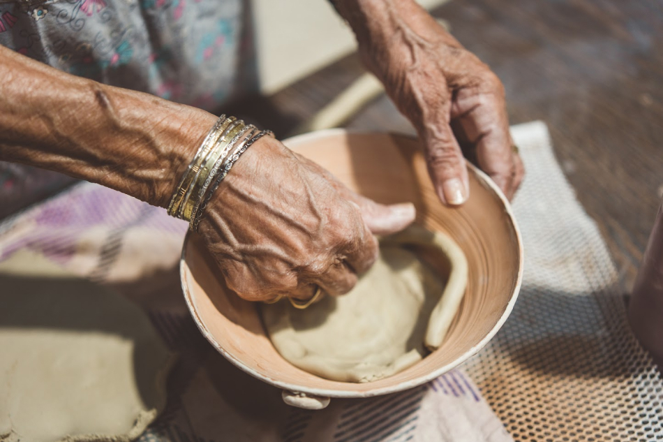 Руки пожилой женщины творят из глины