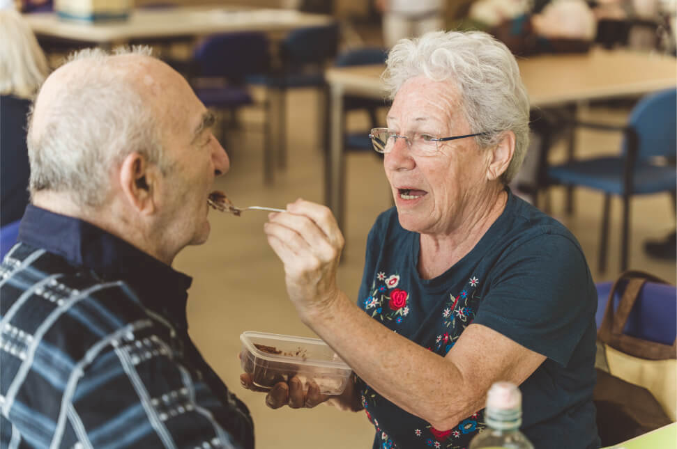 Elderly woman feeding an elderly man