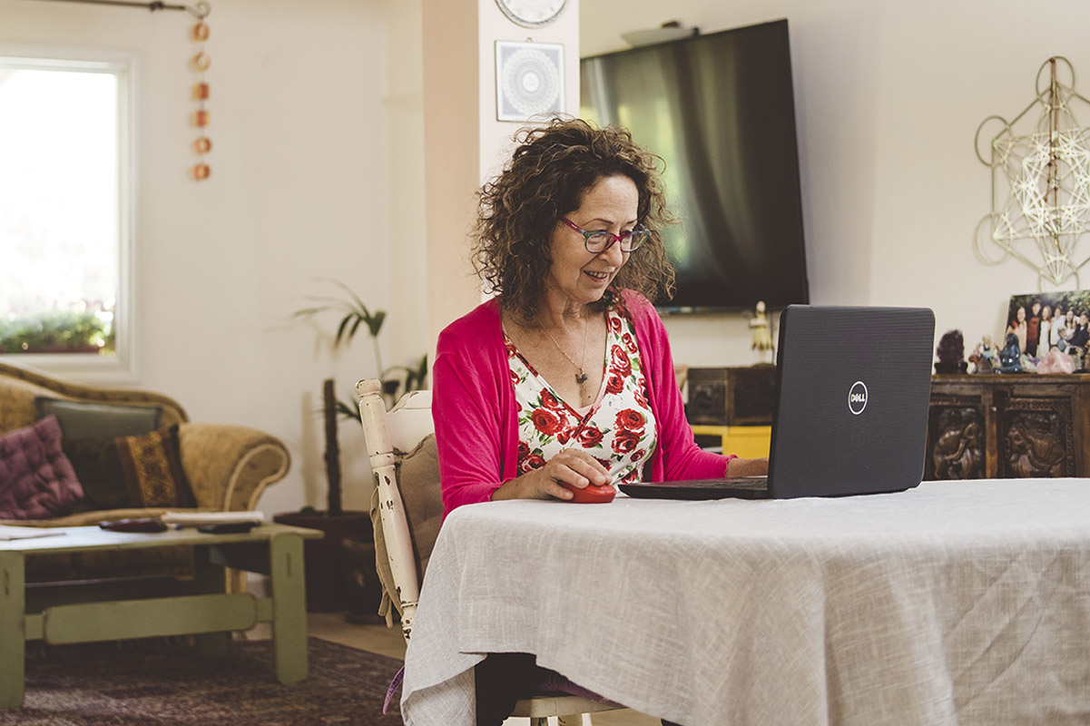 אישה יושבת ליד שולחן ומשתמשת בלפטופ