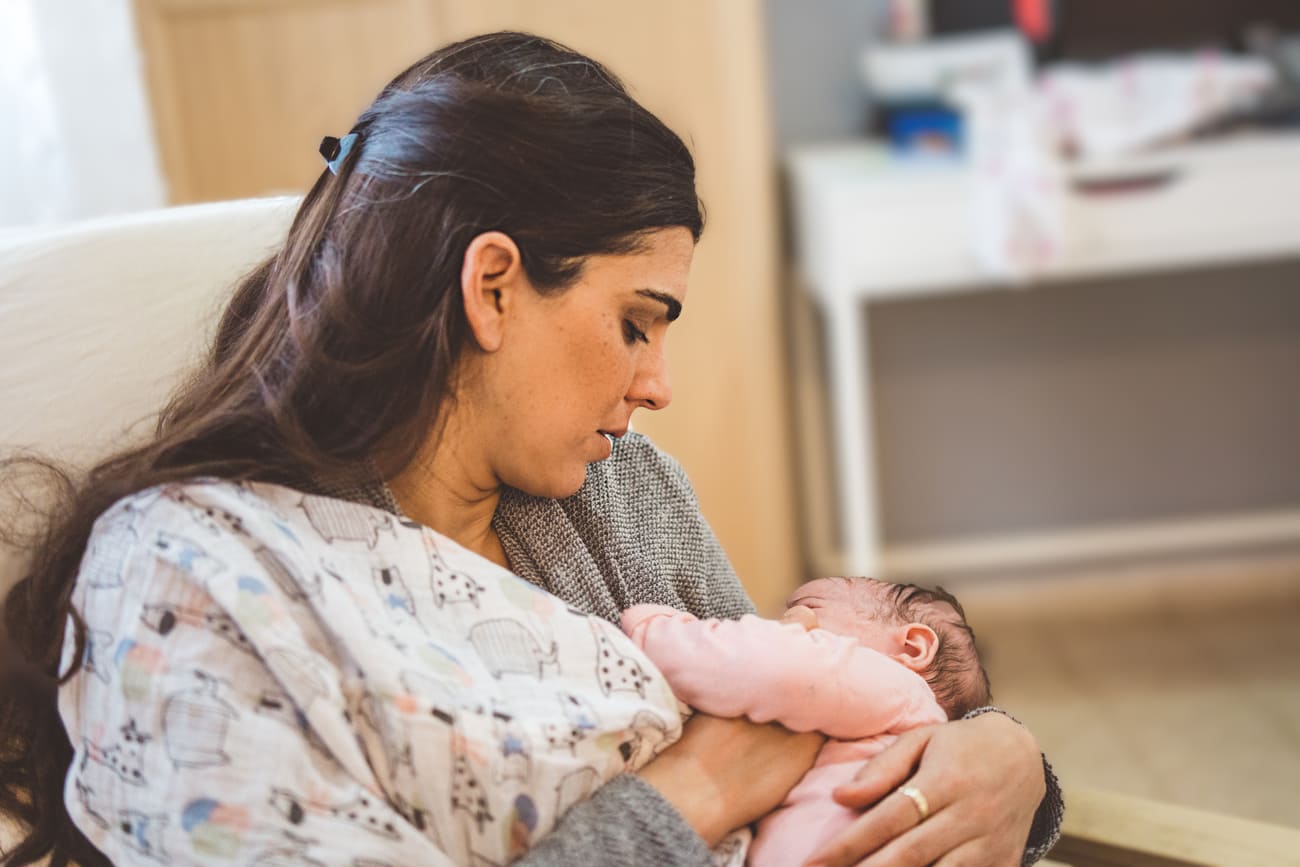 Женщина кормит грудью младенца, сидя на стуле