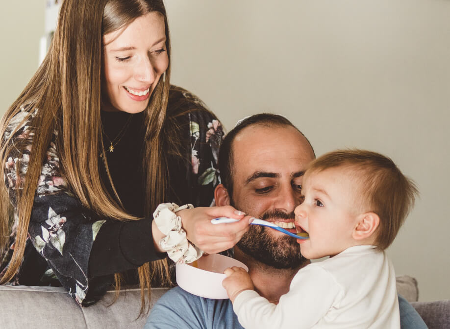 Mother feeding a baby who is sitting on his father